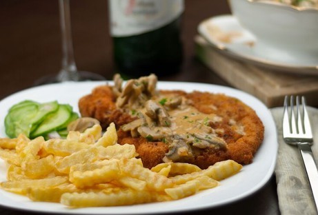 A breaded schnitzel with fries and cucumber salad