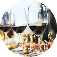 Verres de vin rouge alignés sur une table à côté de plateaux de bouchées sur cure-dents