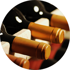 Gros plan sur des bouteilles de vin à capsule dorée couchées dans un casier en bois