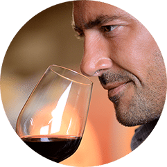 Un homme approche un verre de vin rouge de son nez pour en humer les arômes