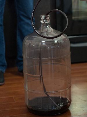 Tourie en verre vidée, avec une canne de soutirage à l'intérieur et une mince couche de lie foncée au fond