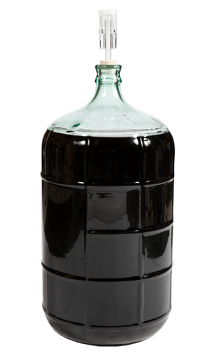Dame-jeanne en verre remplie de vin rouge foncé et munie d’un barboteur