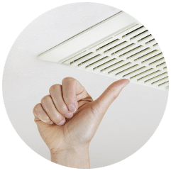 Une main fait un pouce levé sous une grille de ventilation au plafond