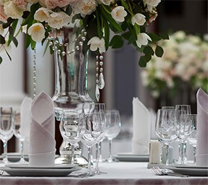 Table de banquet dressée avec des fleurs blanches, des serviettes pliées et des rangées de verres à vin