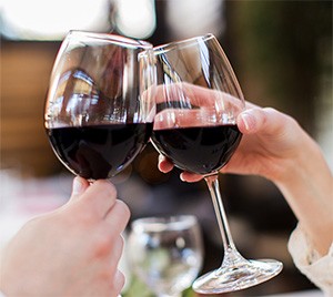 Deux personnes trinquent avec des verres de vin rouge au-dessus d'une table