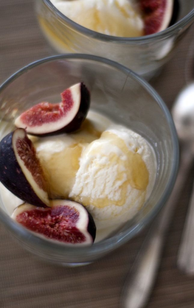 Two individual servings of homemade ice cream topped with sliced fresh figs and local honey