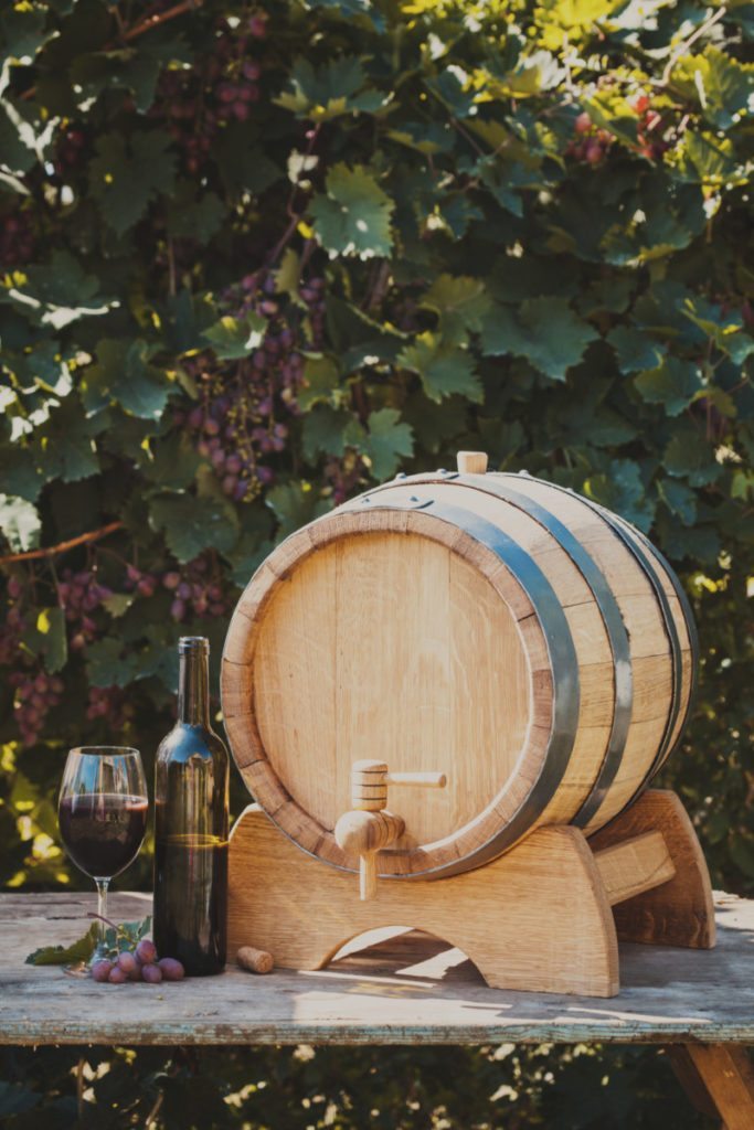 The wooden barrel with wine on a table outdoor. Winery culture