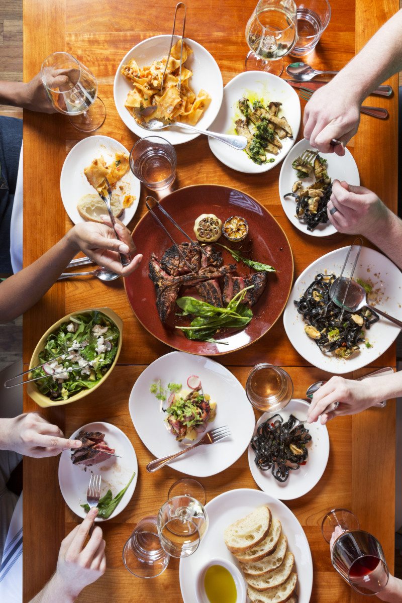 An overhead shot of people eating a family style meal.